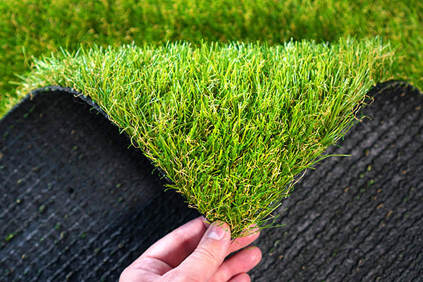 Hand holding an artificial grass roll. Greenering with an artificial turf.