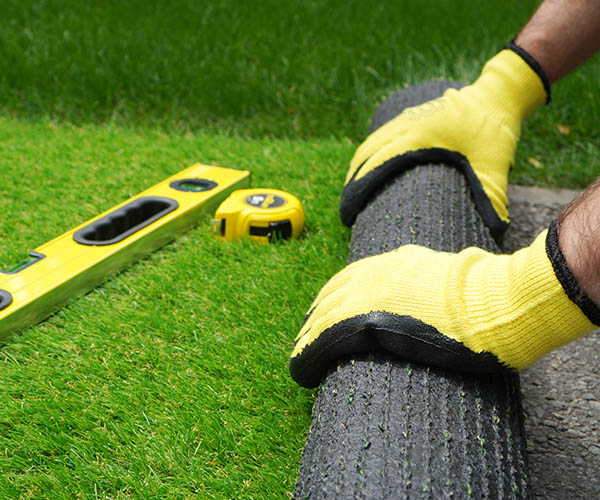 Man's hands spread an artificial turf roll