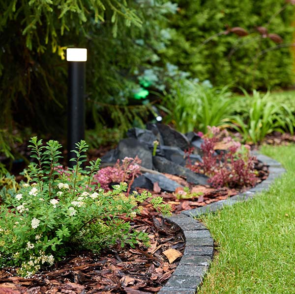 A beautifully picturesque garden filled with an array of vibrant plants and decorative rocks within a lush landscape