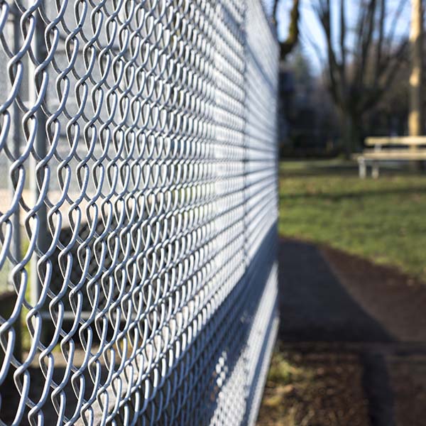 metal fence cage in a soccer field, park bench behind, sunny day, closeup, detail, horizontal