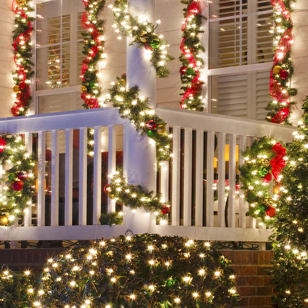 Close up detail of a Victorian-style home in a Christmas town/village that is beautifully decorated for the Holiday Season with lights, ornaments, wreaths and garlands.