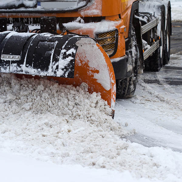 front view of an orange snow plug working on a city street